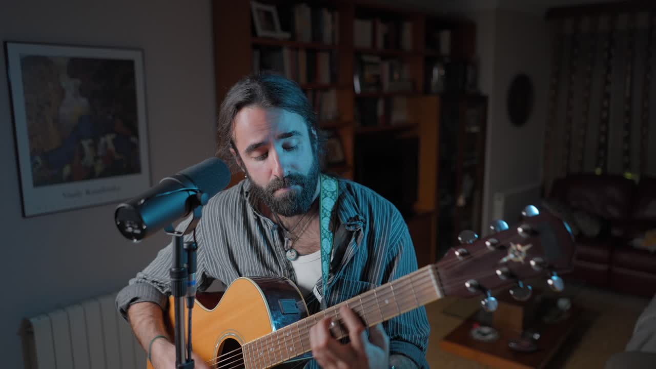 hombre tocando la guitarra acústica en un estudio casero