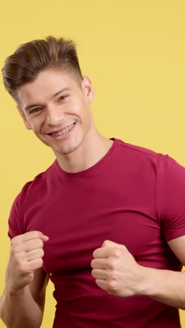 young man with braces flexing his muscles on a yellow background