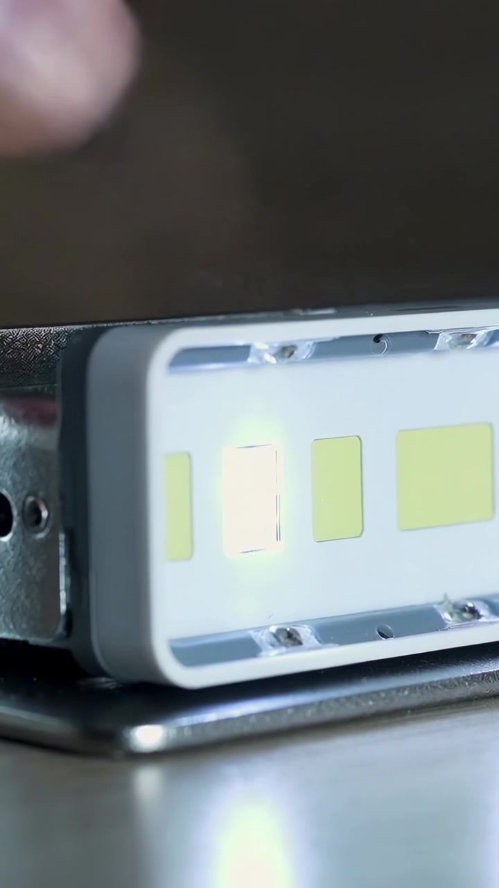 Vertikal video: En nærmende fingerspids trykker på et LED-modul på en bænk og tester lysstyrken på den venstre chip.