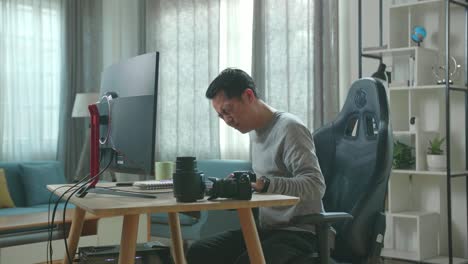asian cameraman in long sleeved t-shirt and black pants having backache while using desktop computer for working at home.