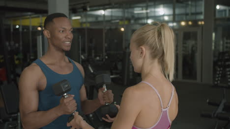 caucasian female monitor and an athletic african american man in the gym.