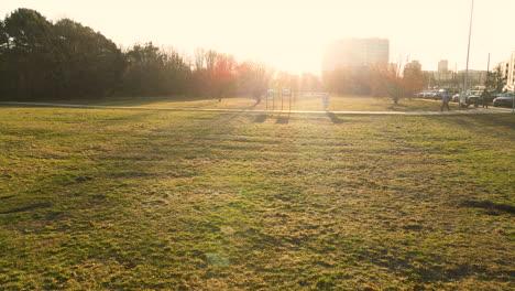 woman with a dog walking behind a man in park prezydenta ronalda reagana during a sunset with in the background high appartments of the przymore district in gdansk