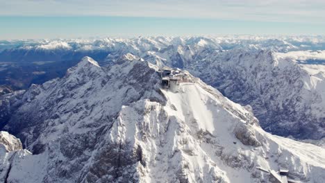 aerial orbiting around the summit of zugspitze a snowy mountain peak in the alps with an impressive building on top