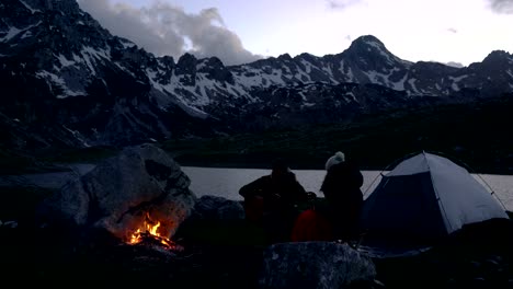 couple of travelers at dusk near a campfire