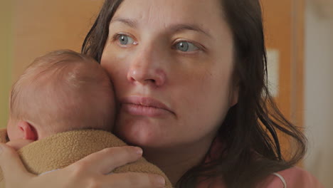 tierd mother rests tenderly holding newborn baby for the first time in hospital, portrait