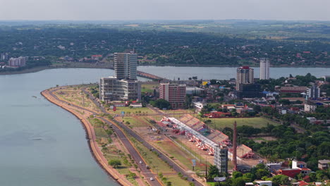 an impressive aerial shot showcasing the vibrant shopping costanera and sambódromo, with the city of encarnación and the river in the background.