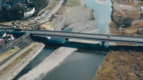 automóviles conduciendo en el puente mutsumi sobre el río cerca de la plaza de ladrillo en el parque fussa-minami del espacio verde del río tama, tokio, japón