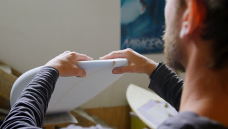 man examining a surfboard 4k