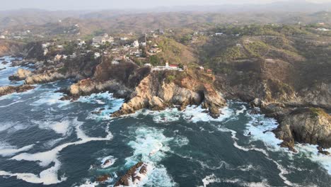 long pull back in oaxaca shore with view of mountains, cliff and small lighthouse