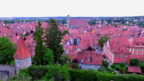a drone flies backwards over the old town and the red roofs of the houses and the city's green park aerial view