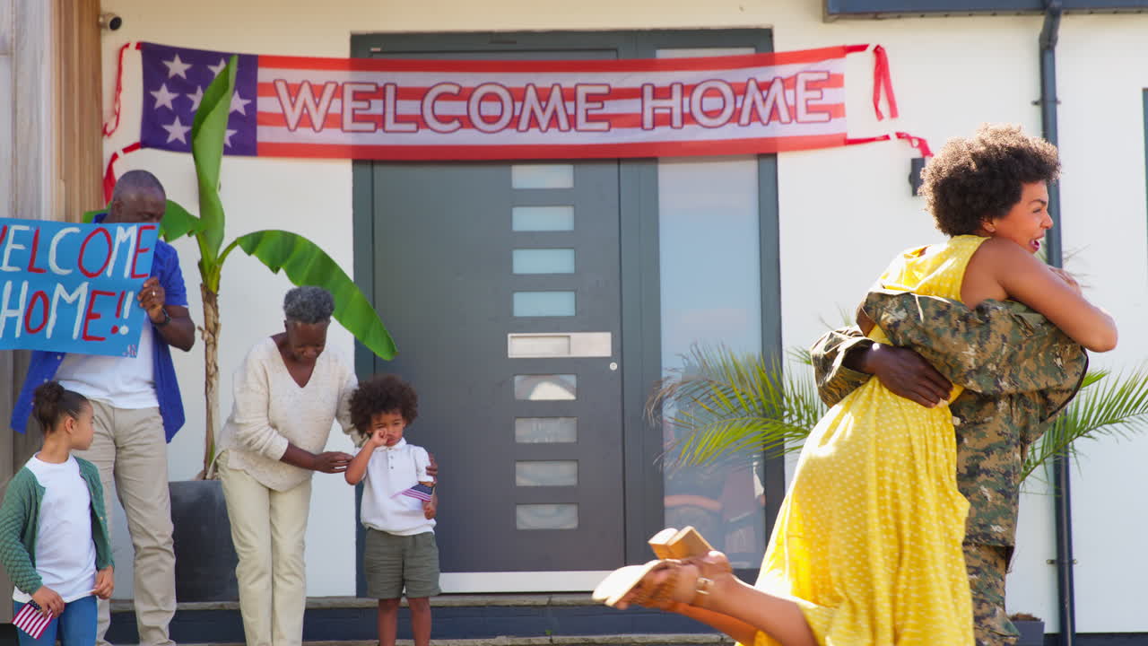esposa abrazando a su marido como una familia multigeneracional dando la bienvenida al padre del ejército a casa de licencia con una bandera