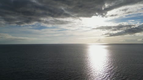 Vista-Alta-De-Drones-Aéreos-Del-Océano,-Reflejo-Del-Sol-En-La-Hora-Dorada-Escondido-Detrás-De-Las-Nubes