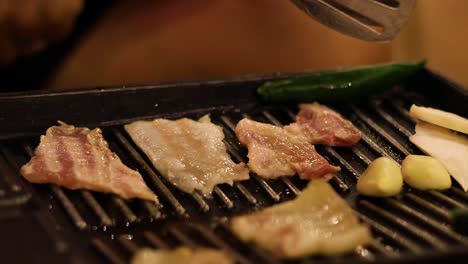 cooking bacon, garlic, and peppers on a grill