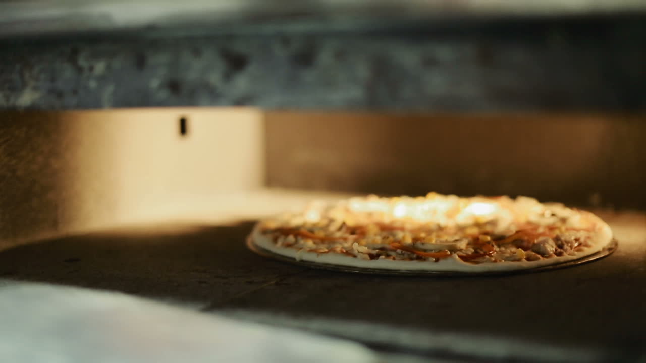Pizza stekes i ovnen. Tar ut pizza fra ovnen på restaurantkjøkkenet.