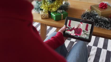 Caucasian-man-using-tablet-for-christmas-video-call,-with-smiling-man-on-screen