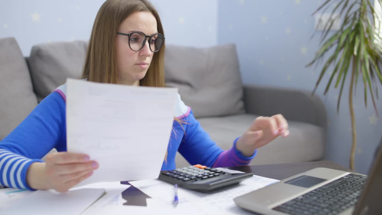 mujer usando calculadora para calcular facturas domésticas en el hogar, haciendo papeleo para pagar impuestos