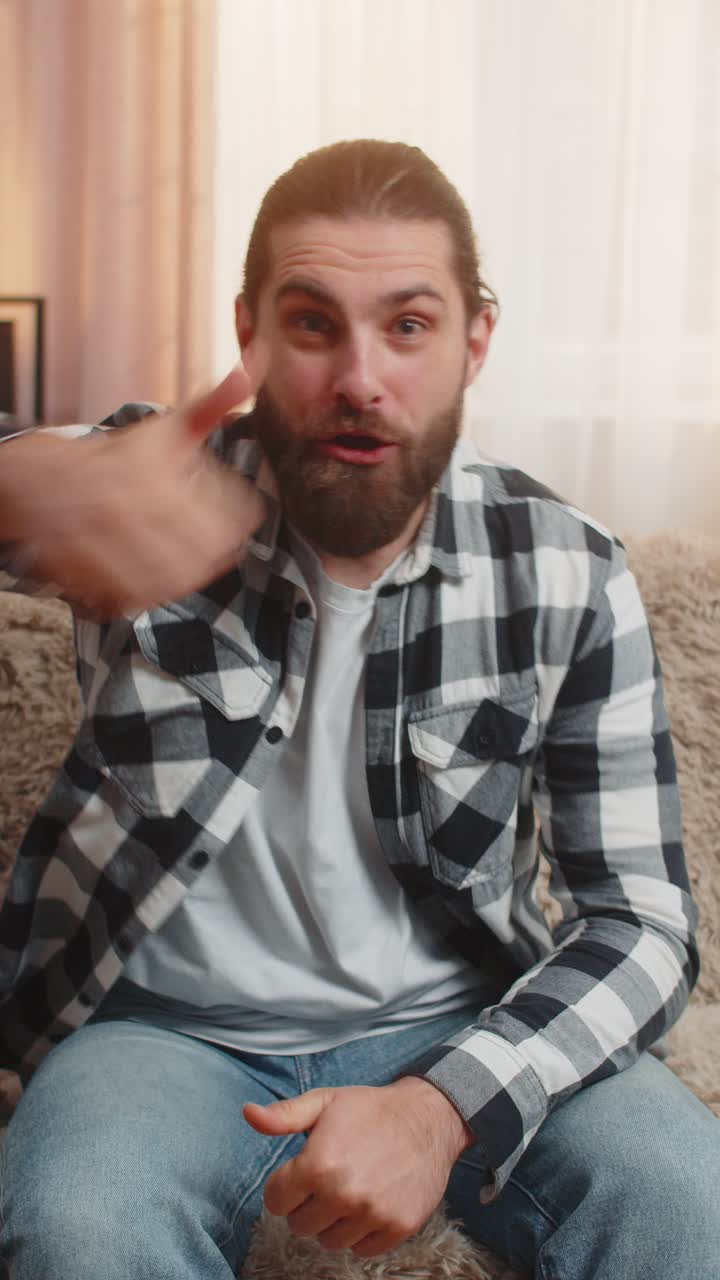 Man changing like to dislike at home sofa thumbs switch ironic mood quick gesture playful twist