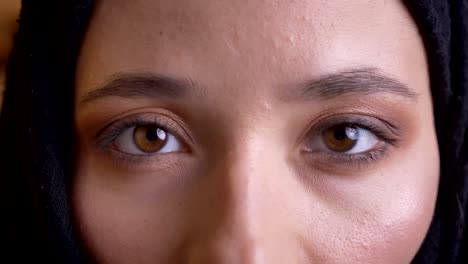 closeup portrait of young beautiful muslim female face in black hijab looking with pretty brown eyes straight at camera