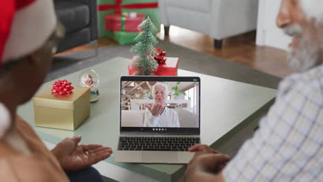 feliz pareja afroamericana senior en videollamada en computadora portátil con una amiga en tiempo de navidad
