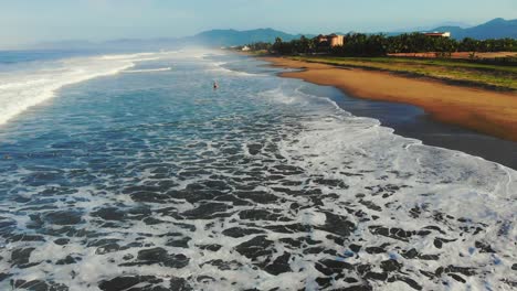 Flying-above-coast-towards-a-resort-amongst-palm-trees-in-Zihuatanejo-Mexico