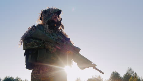 hombre armado con uniforme militar debería estar contra el cielo el sol brilla detrás de su armadura
