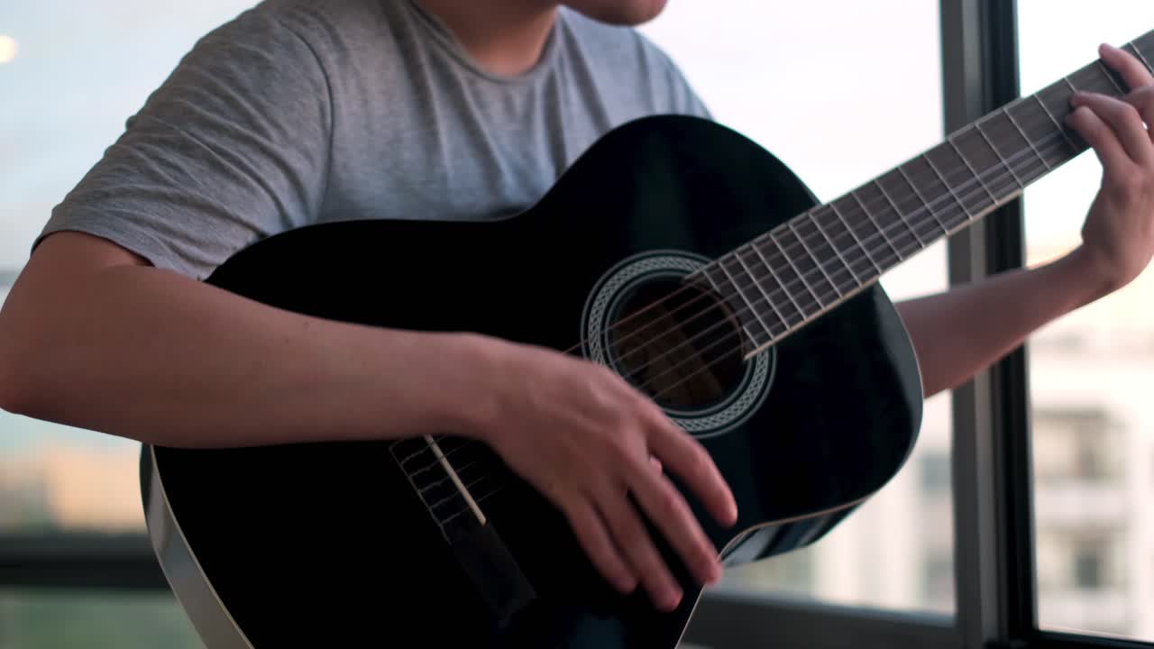 hombre tocando la guitarra acústica por la ventana