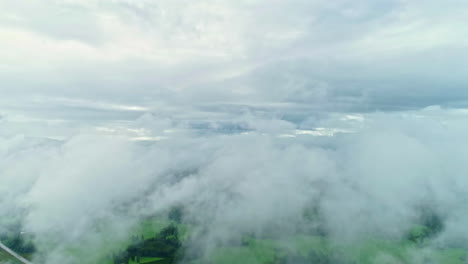 Dolly-backwards-through-misty-clouds,-mid-forest-glade-depicted-underneath