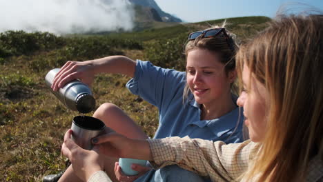 two friends enjoying a hot drink in the mountains