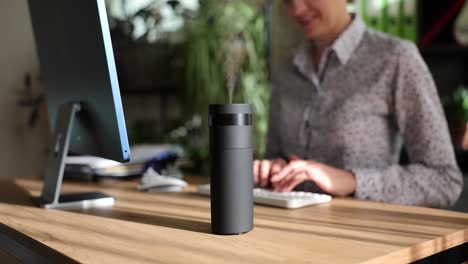 humidifier on an office desk with a person working in the background