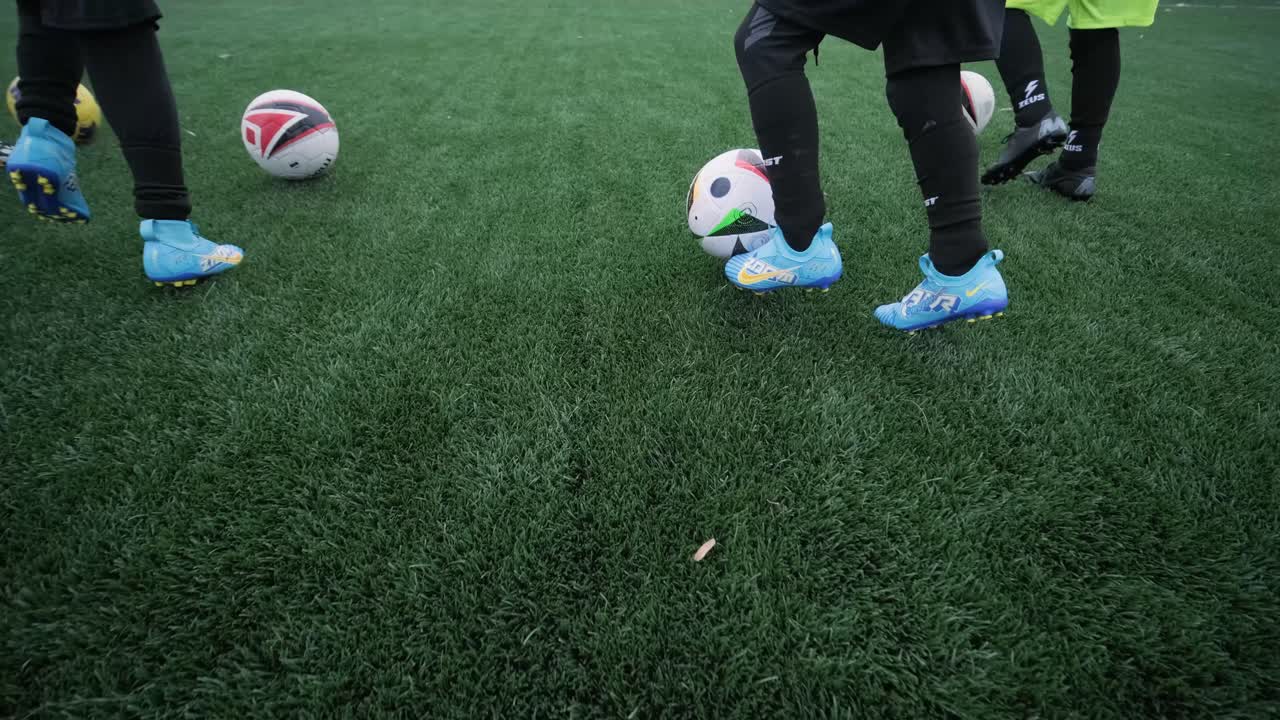 Et børnefodboldhold træner på stadion under vejledning af en træner. Børn i sportstøj øver boldøvelser, forbedrer teknik og udvikler teamwork på den grønne bane