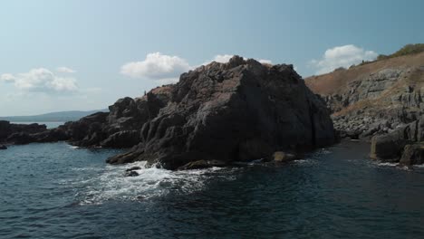 Aerial-pan-shot-around-big-rocks-in-the-sea,-sunny-summer-day-1