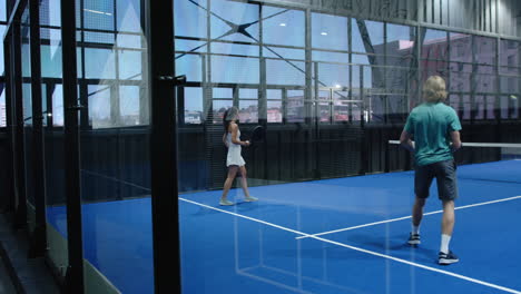 diverse athletes playing padel tennis on blue indoor court, focusing on teamwork