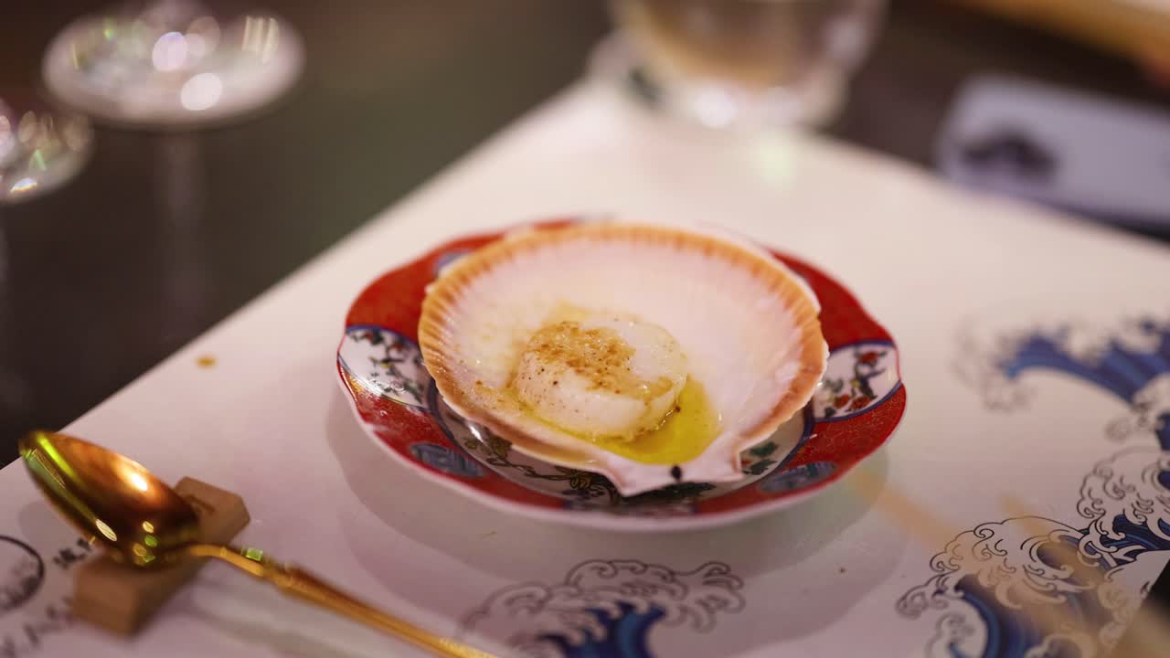 Scallop being seasoned and cooked in shell