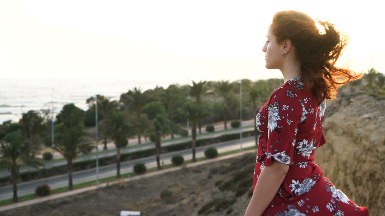 Woman in red dress overlooking palm trees at sunset