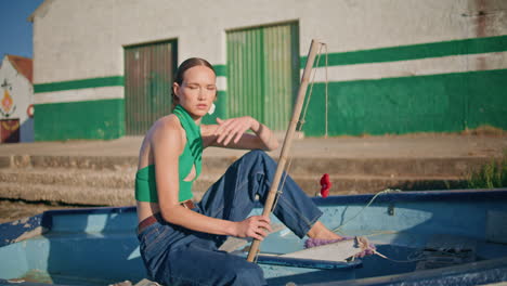 modelo de moda posando en un barco a la luz del sol de verano. niña tranquila con caña de pescar