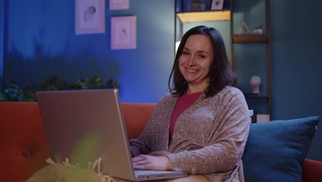 Woman-freelancer-lying-on-sofa,-working-on-laptop-notebook-screen-studying-shopping-online-at-home