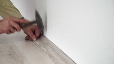 man using a hammer to nail laminate batten