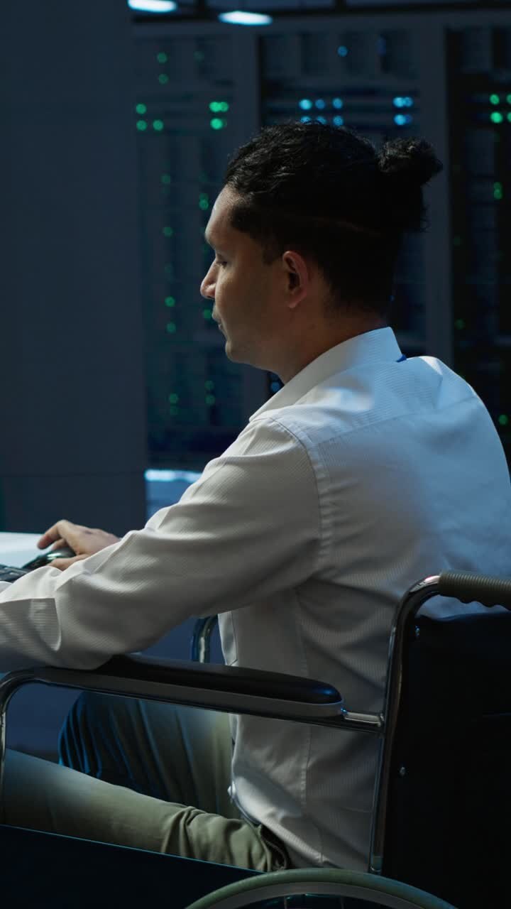 Mand i kørestol arbejder på computer i datacenter