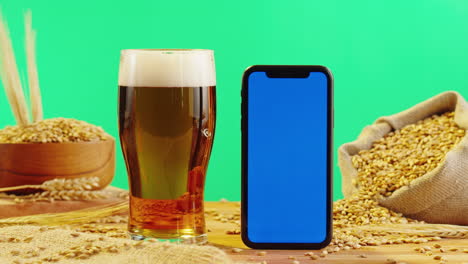 beer and smartphone mockup on wooden table with barley