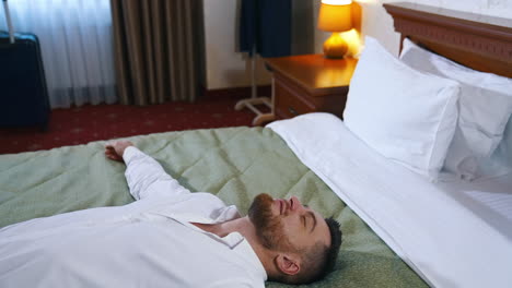 tired businessman on bed. young man falling on bed after a difficult business day. handsome man resting after arrival to a hotel room.