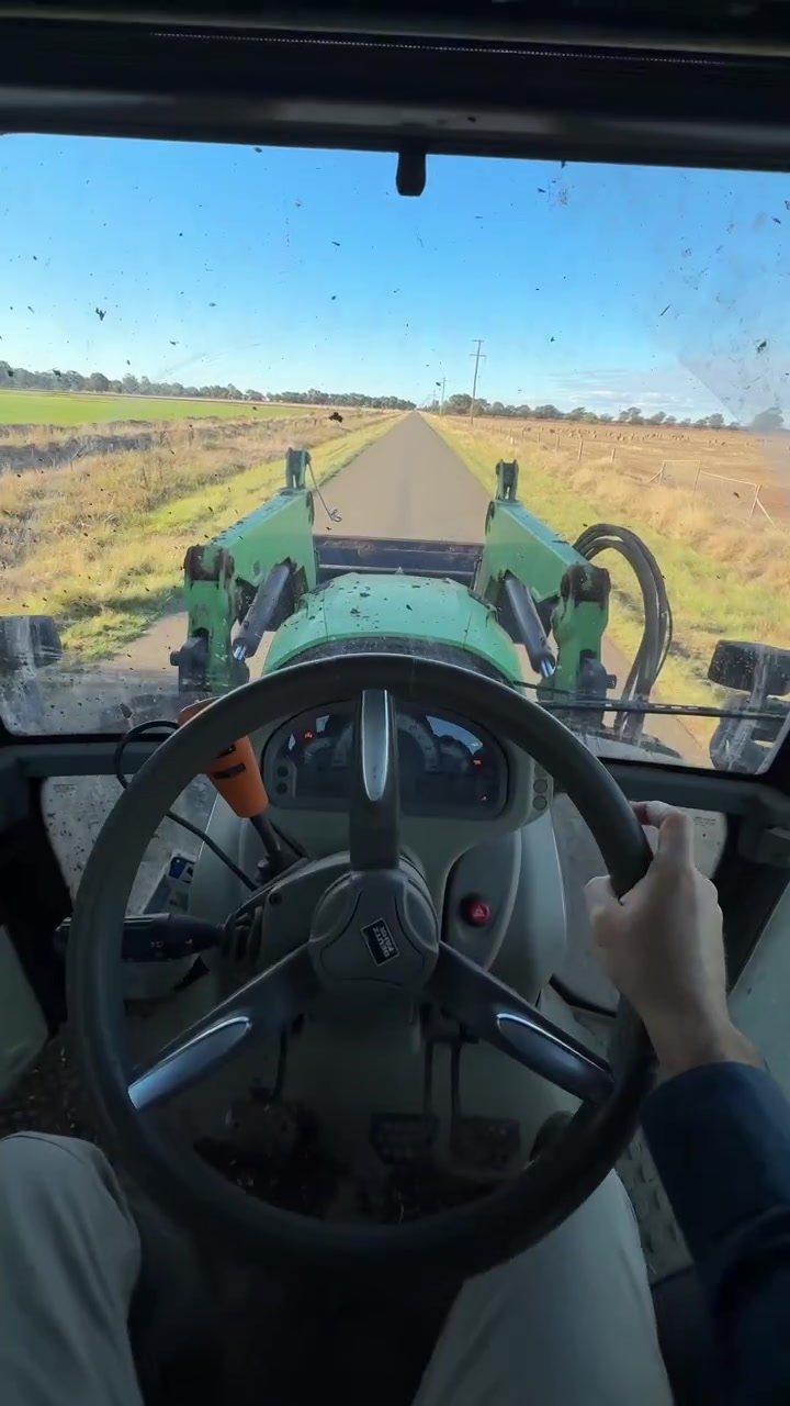 Inquadratura verticale in soggettiva dall'interno della cabina di un trattore che percorre una strada di campagna rurale