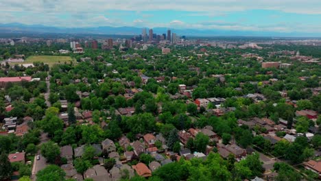 Summer-in-downtown-Denver-Colorado-aerial-drone-front-range-Rocky-mountain-peak-foothills-landscape-Flat-irons-Red-Rocks-city-skyscrapers-neighborhood-homes-blue-skies-clouds-forward-pan-up-reveal