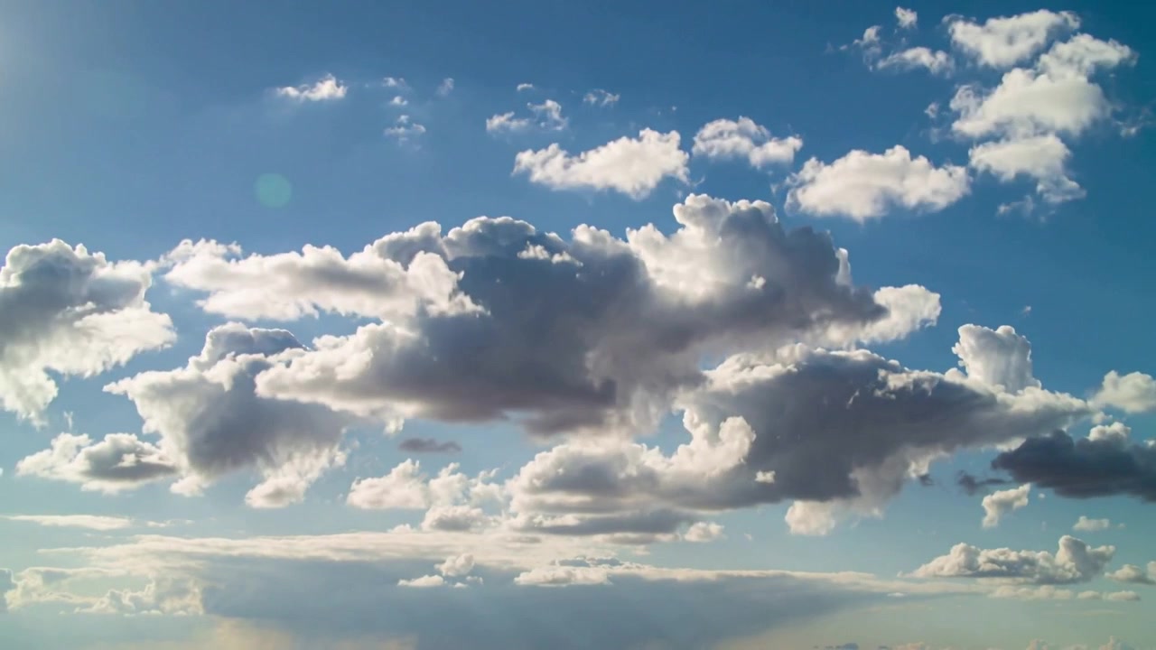 Grande nuvola cumuliforme in evoluzione che si gonfia e si illumina nel cielo sopra l'orizzonte, spinta dalla luce solare.