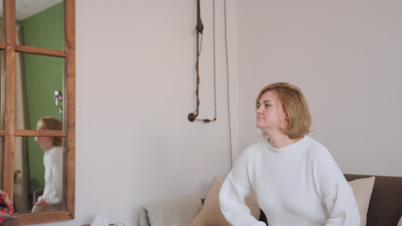 Side view of therapist guiding smiling guest past wooden door toward sofa in modern therapy office with green and white walls and black coat rack, both walking warmly into session room