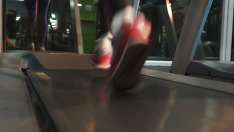 Female muscular feet in sneakers running on the treadmill at the gym. Concept for fitness, exercising and healthy lifestyle.