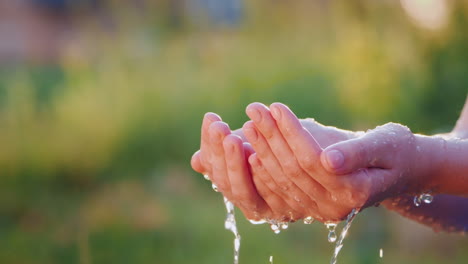 Wasser-Fließt-In-Offene-Menschliche-Handflächen-Spritzt-Effektiv-In-Der-Sonne-Auseinander-Zeitlupenvideo