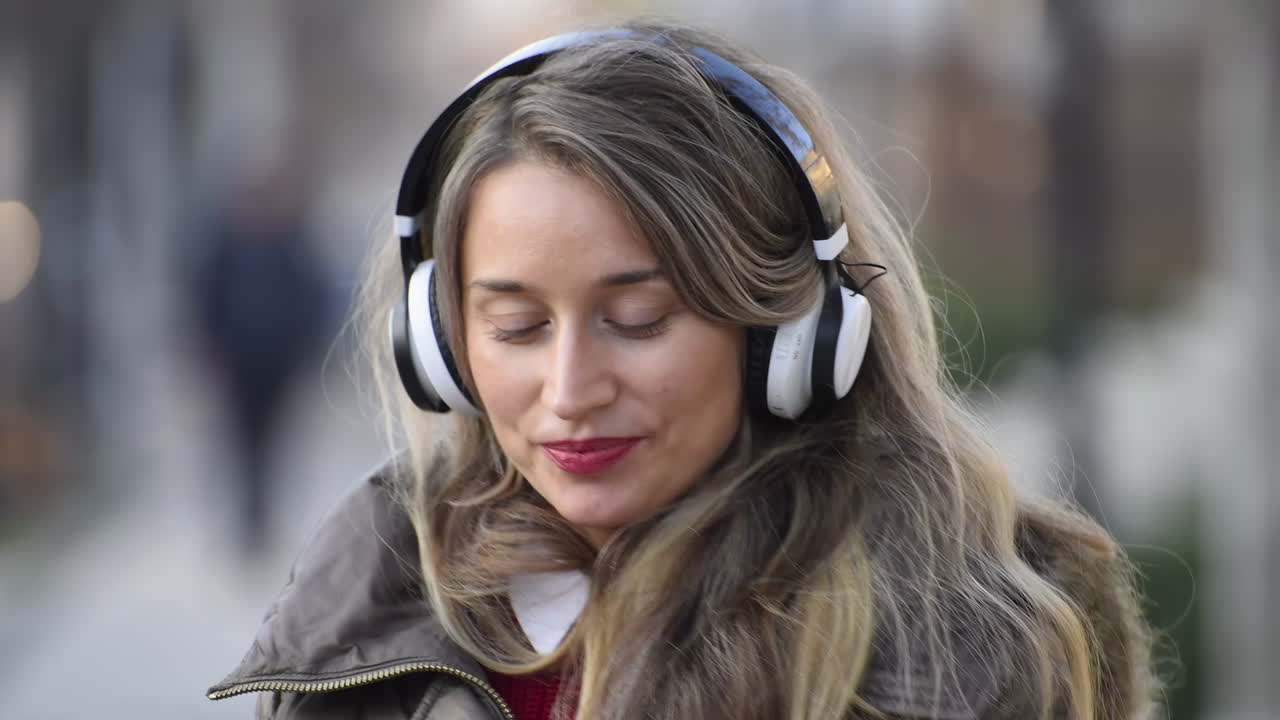 Woman listening to music in her headphones while singing along and dancing in the street