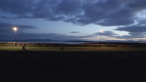 aerial shot of nimmo's pier in galway, gliding along the illuminated path under a dramatic twilight sky. galway city