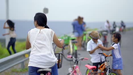 asian women sitting with their bicycles watching the children play happily.