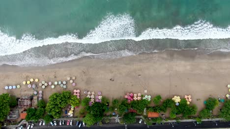 Playa-Exótica-Tropical-Con-Sombrillas-Y-Océano-De-Agua-Azul,-Vista-Aérea-De-Arriba-Hacia-Abajo